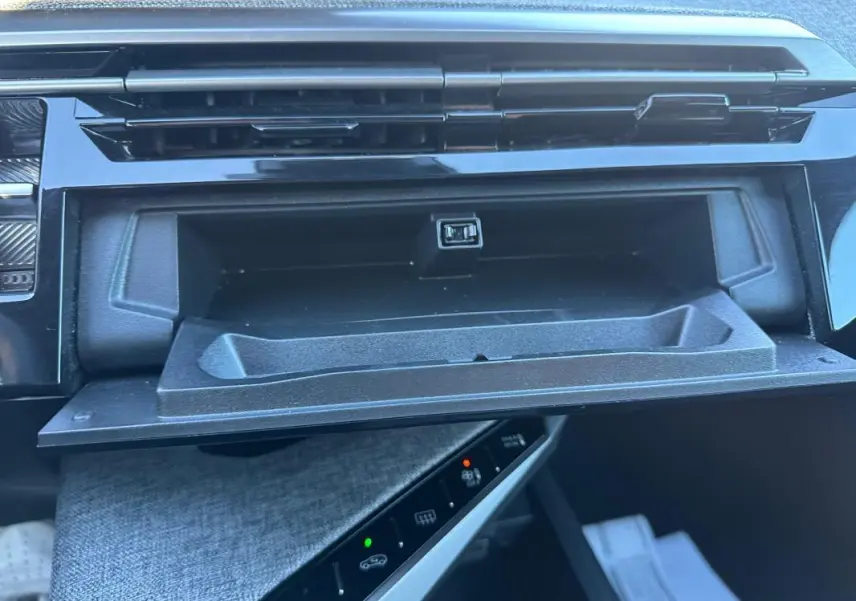 Gros plan intérieur sur la boîte à gants ouverte du Peugeot 3008 blanc, version Hybrid 145 e-DCS6 Allure.