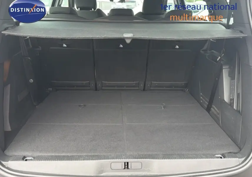 Coffre ouvert vu de l'arrière d'un Peugeot 5008 bleu Célèbes Métal, avec banquette arrière rabattue et cache-bagages déployé.