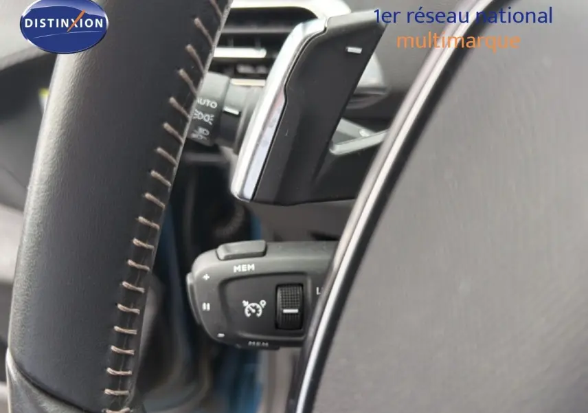 Gros plan sur la commande de régulateur de vitesse derrière le volant en cuir noir du Peugeot 5008 bleu Celebes.