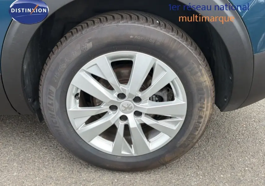 Gros plan sur la roue avant droite d’un Peugeot 5008 bleu Célèbes Métal avec jante alliage argentée.