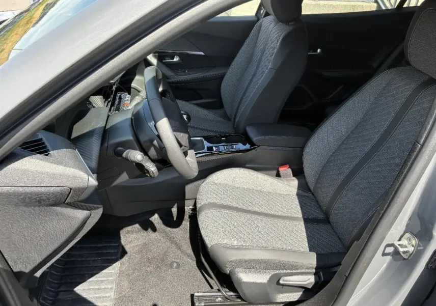 Vue intérieure côté conducteur du Peugeot 2008 2024 sellenium, montrant les sièges tissu gris et la console centrale moderne.