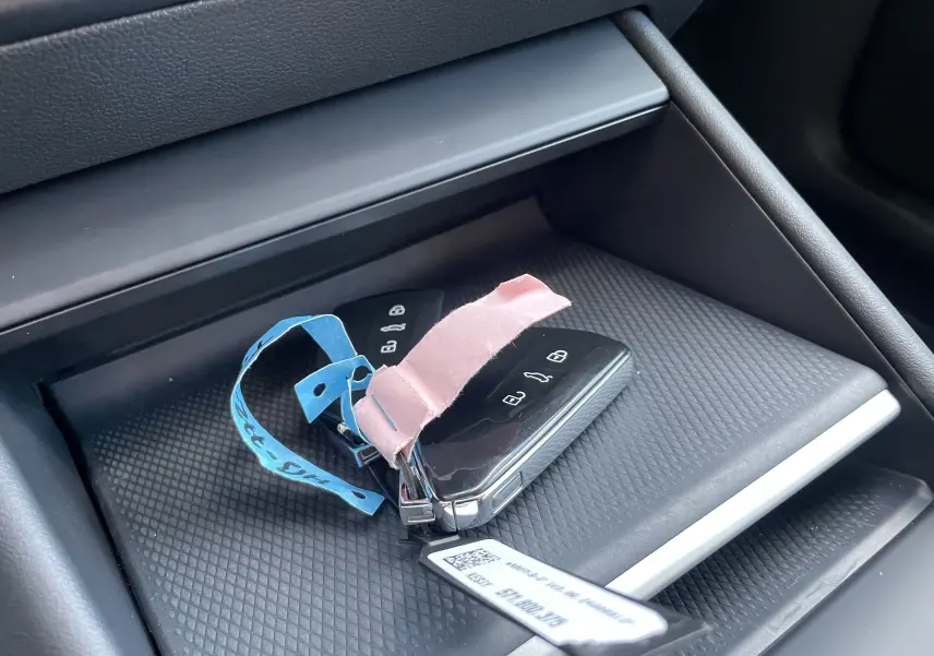 Gros plan sur la console centrale du Volkswagen Tiguan 2024 avec clés et porte-clés posés sur un tapis texturé noir.