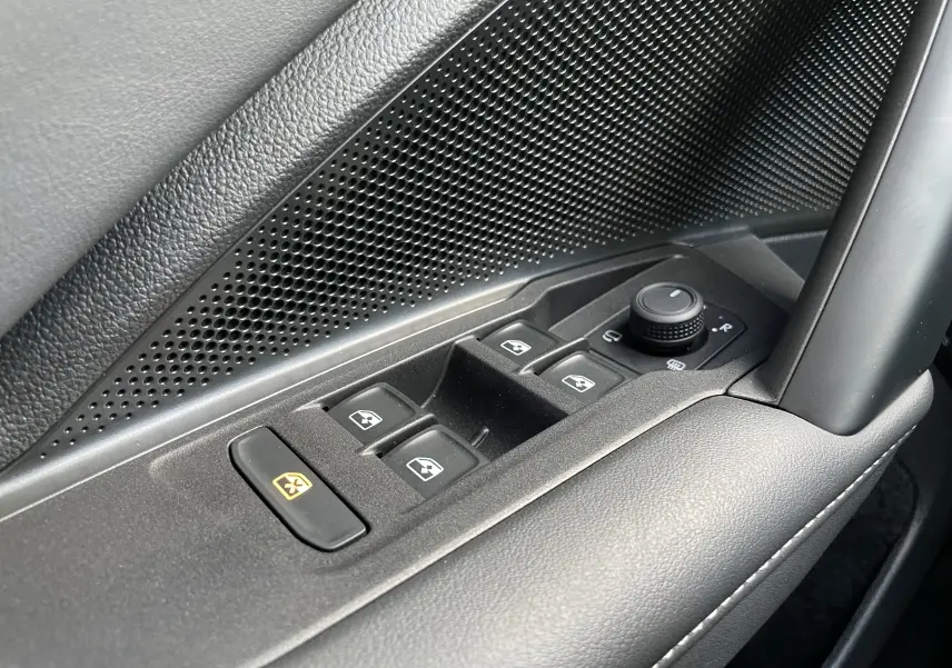 Gros plan sur les commandes des vitres et rétroviseurs côté conducteur du Volkswagen Tiguan 2024 en noir, avec finition texturée.