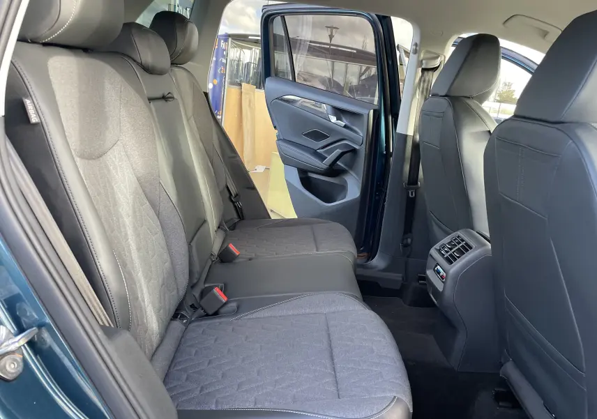 Vue intérieure arrière droite du Volkswagen Tiguan 2024 en Nightshade Blue, sièges gris noir et porte ouverte.