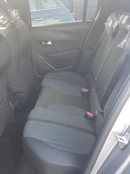 Vue intérieure côté droit des sièges arrière gris de la Peugeot 208 Hybrid 110 e-DCS6 Allure 2025 avec habillage tissu et cuir.