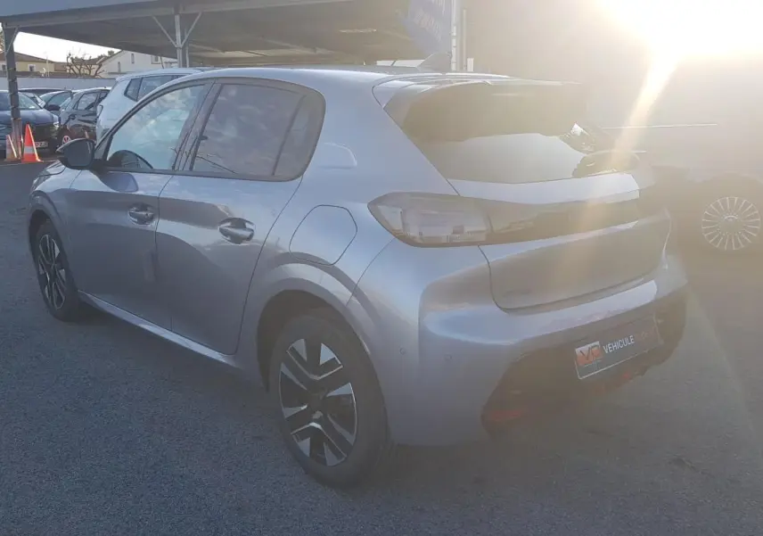 Vue 3/4 arrière droite d'une Peugeot 208 Hybrid 110 gris métallisé avec jantes alliage et antenne requin.