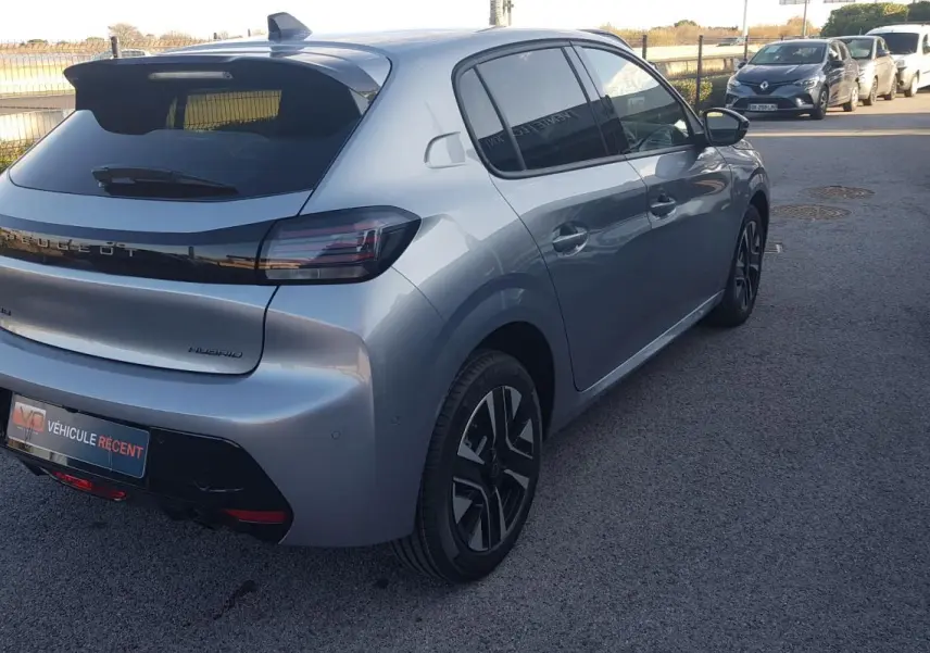 Vue 3/4 arrière droite d'une Peugeot 208 Hybrid 110 gris métallisé avec jantes alliage et antenne requin.