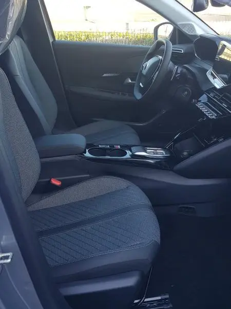 Vue intérieure côté conducteur de la Peugeot 208 Hybrid 110 gris, avec sièges tissu et tableau de bord moderne.