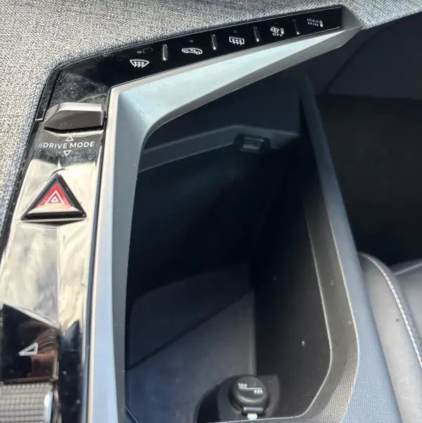 Vue rapprochée de la console centrale du Peugeot 3008 Hybrid 145 e-DCS6 Allure 2025, avec boutons de commandes et prise 12V.