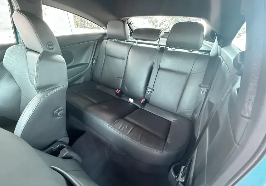 Vue intérieure arrière montrant les sièges en cuir noir de l'Opel Astra OPC bleu, côté droit ouvert.