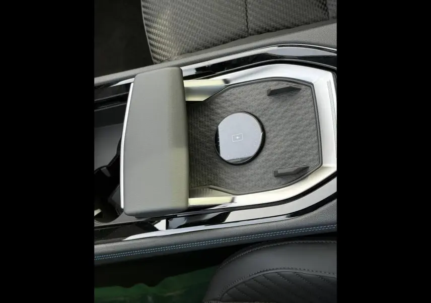Détail de la console centrale noire avec accoudoir gris et surface de recharge sans fil du Renault Austral 2026.