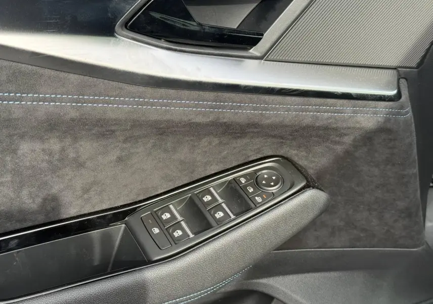 Détail de la porte côté conducteur du Renault Austral 2026, revêtement noir avec surpiqûres bleues et commandes de vitres.