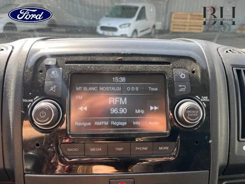 Vue rapprochée de la console centrale du tableau de bord avec écran tactile et commandes audio du Citroën Jumper blanc.