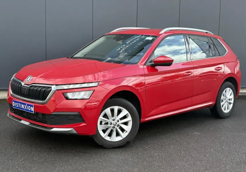 Vue 3/4 avant gauche d'un Skoda Kamiq TSI 110 DSG Ambition rouge Velvet avec jantes alliage 16 pouces et barres de toit alu.