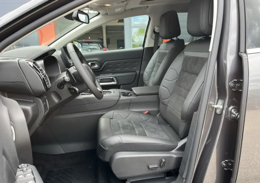Intérieur avant droit du Citroën C5 Aircross Hybrid 2025 avec sièges cuir et alcantara gris, tableau de bord moderne et volant multifonction.