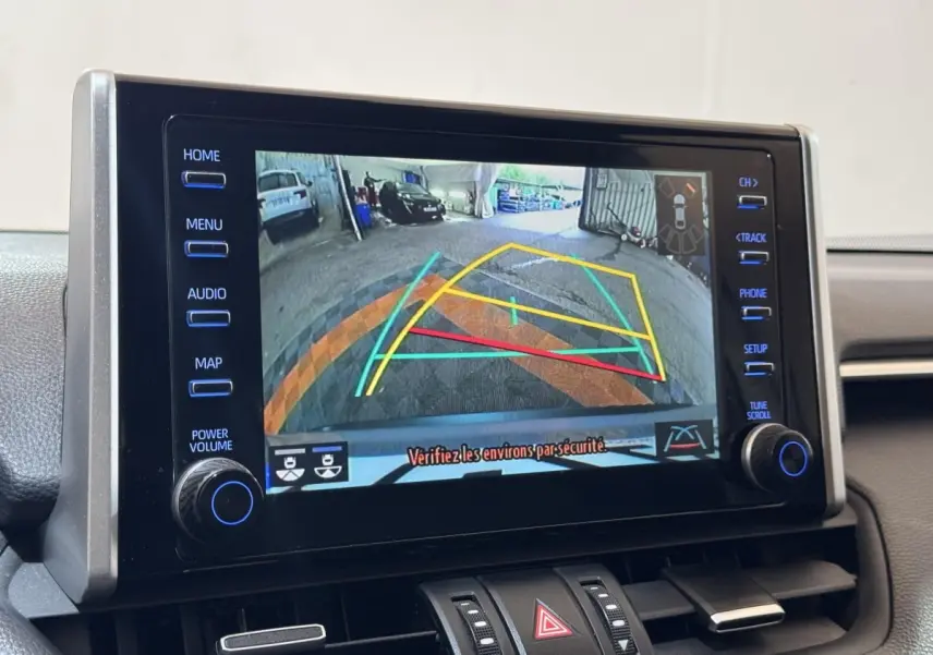 Écran tactile central montrant la caméra de recul avec guidage dynamique du Toyota RAV4 hybride gris clair, vue intérieure frontale.