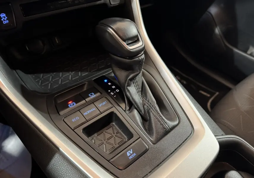 Gros plan sur la console centrale noire avec levier de vitesse automatique et boutons modes conduite du Toyota RAV4 gris clair 2021.