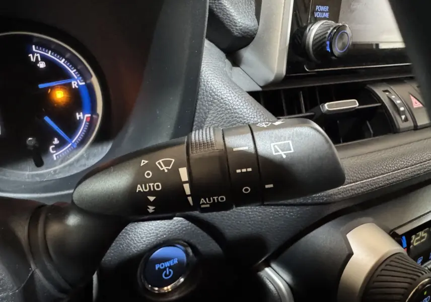 Gros plan sur la commande d'essuie-glace et le bouton Power bleu du tableau de bord intérieur du Toyota RAV4 gris clair hybride 2021.