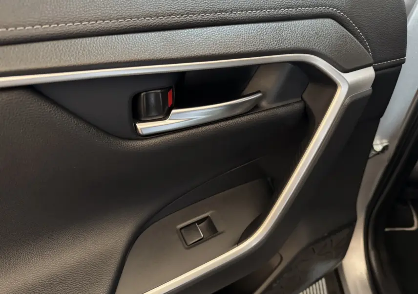 Poignée intérieure côté gauche en métal brossé sur porte noire du Toyota RAV4 Hybride 2021.