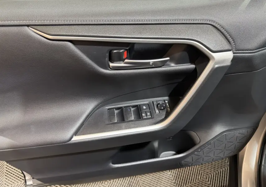 Gros plan sur la porte avant gauche noire du Toyota RAV4 hybride 2021 avec commandes électriques et poignée argentée.