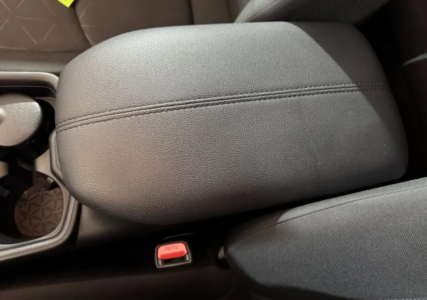 Accoudoir central en cuir noir avec bouton de ceinture rouge, intérieur du Toyota RAV4 hybride 2021.