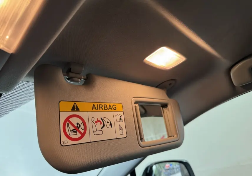 Détail du pare-soleil côté conducteur avec miroir et avertissement airbag dans un Toyota RAV4 gris clair 2021 hybride.