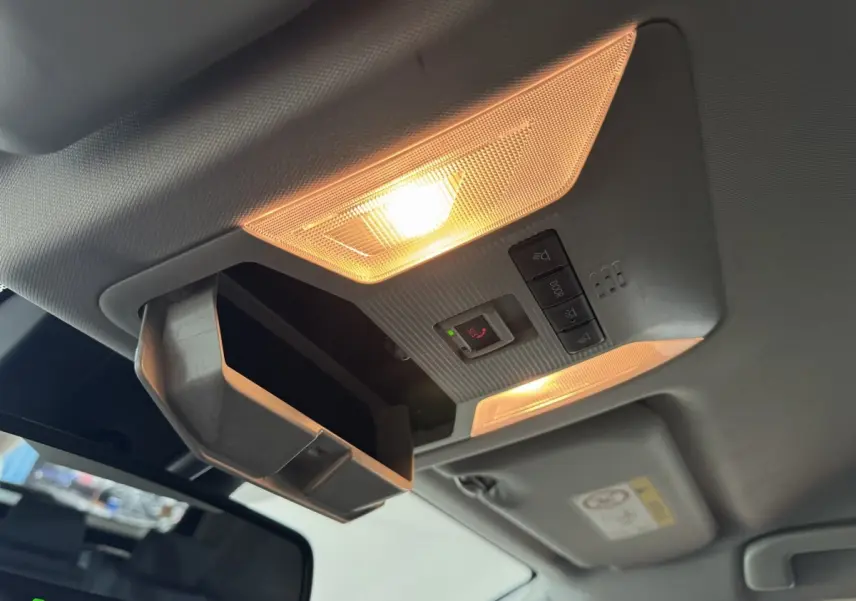 Vue intérieure du plafonnier allumé avec rangement lunettes ouvert dans un Toyota RAV4 hybride gris clair 2021.