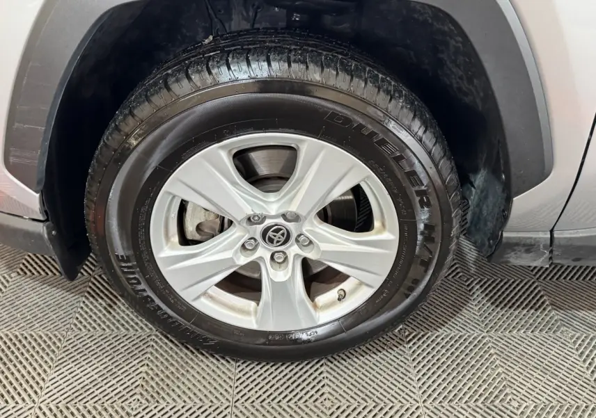 Gros plan sur la roue avant gauche du Toyota RAV4 gris clair, mettant en valeur la jante alliage et le pneu Bridgestone.