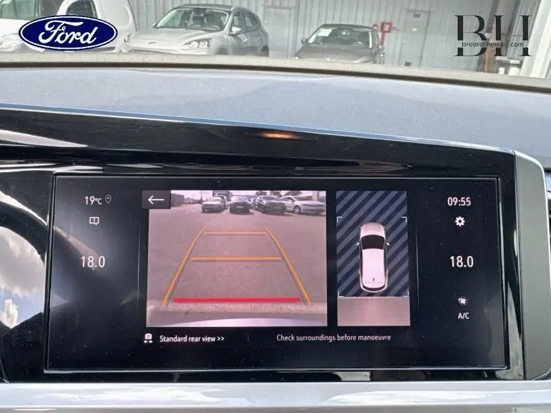 Écran tactile intérieur montrant la caméra de recul et l’aide au stationnement du tableau de bord.