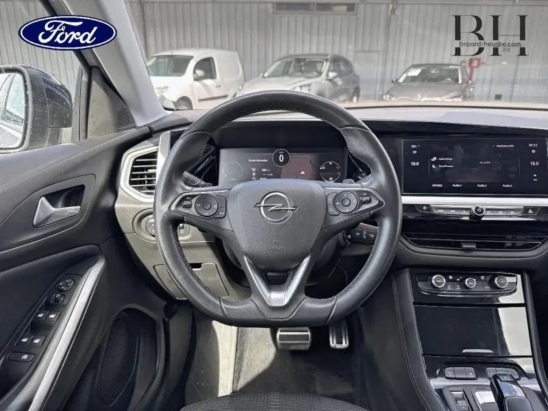 Vue intérieure centrée sur le volant cuir multifonction de l'Opel Grandland 2023, avec tableau de bord numérique et écran tactile.