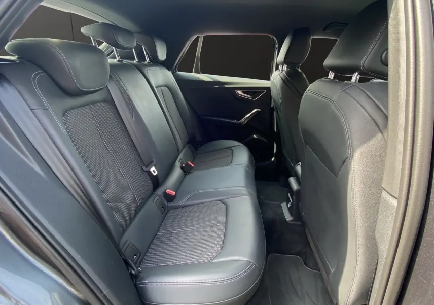 Vue intérieure arrière de l'Audi Q2 35 TDI S-Line avec sièges cuir noir et finitions modernes sur portes.
