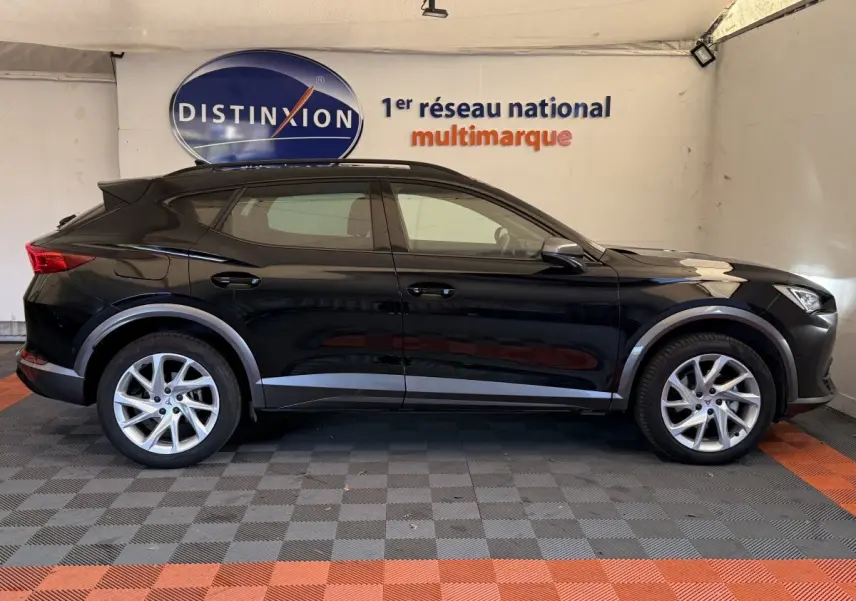 Profil côté gauche d'un SUV CUPRA Formentor noir 2023 avec jantes alliage et protections grises sous un panneau Distinxion.