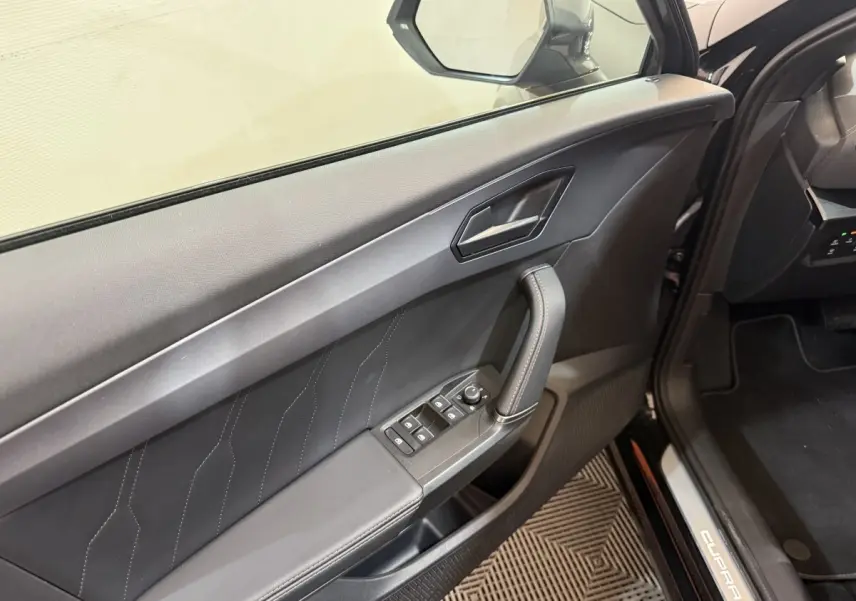 Intérieur côté conducteur noir du CUPRA Formentor 2023, avec commandes vitres et poignée de porte visible.