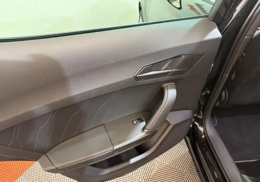 Vue intérieure de la porte arrière gauche noire du CUPRA Formentor 2023 avec poignée et bouton de vitre électrique.