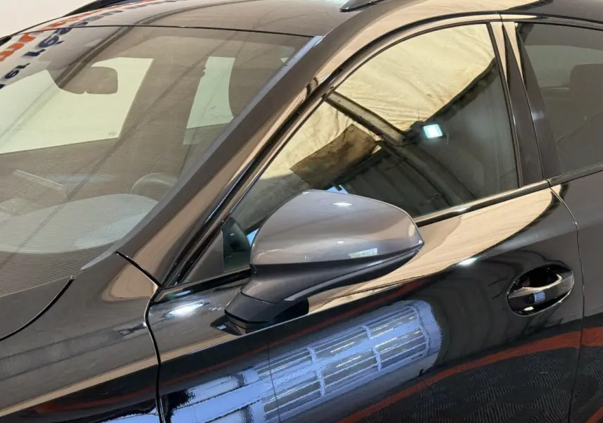 Gros plan sur le rétroviseur côté conducteur d'une CUPRA Formentor noire 2023 avec reflet lumineux sur la carrosserie.