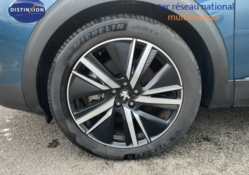 Gros plan sur la roue avant gauche du Peugeot 3008 bleu Célèbes Métal avec jante alliage noire et argent.