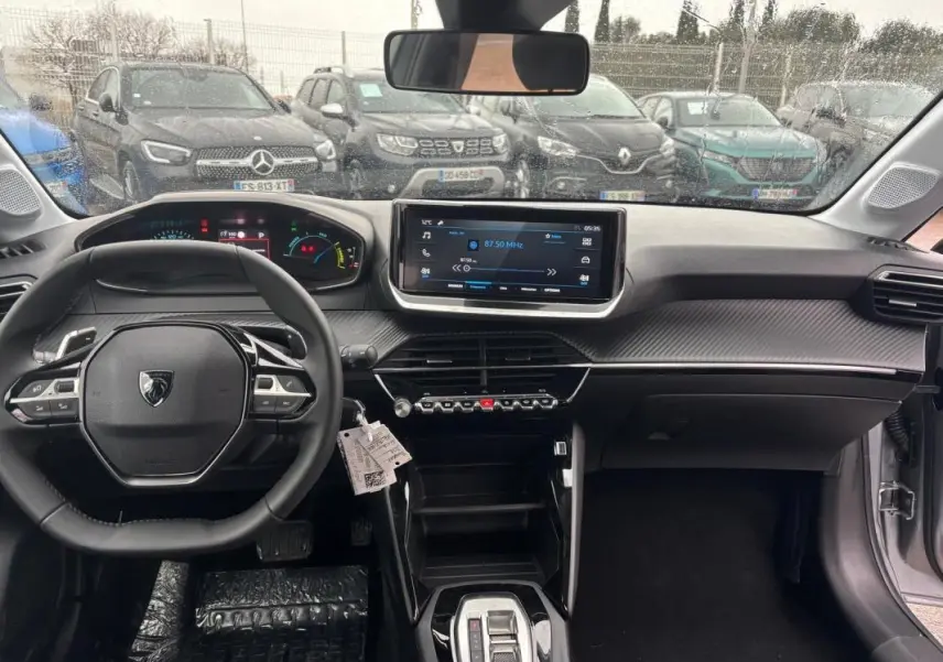 Vue intérieure avant de la Peugeot 208 Hybrid gris, avec volant multifonction, écran tactile et cockpit numérique.