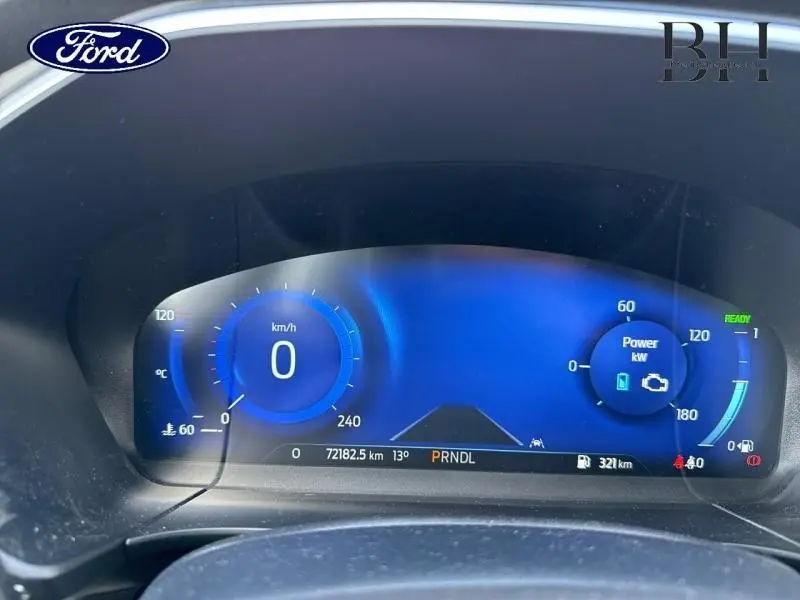 Tableau de bord numérique bleu du Ford Kuga 2023, affichant vitesse à 0 km/h et indicateurs hybrides.