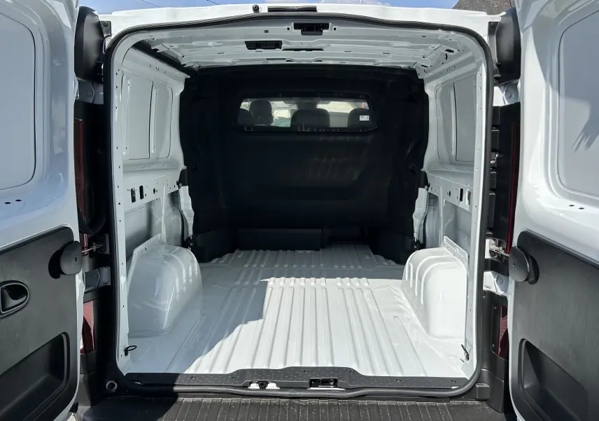 Vue arrière du Renault Trafic cabine approfondie blanc, montrant l’espace de chargement vide et les portes ouvertes.