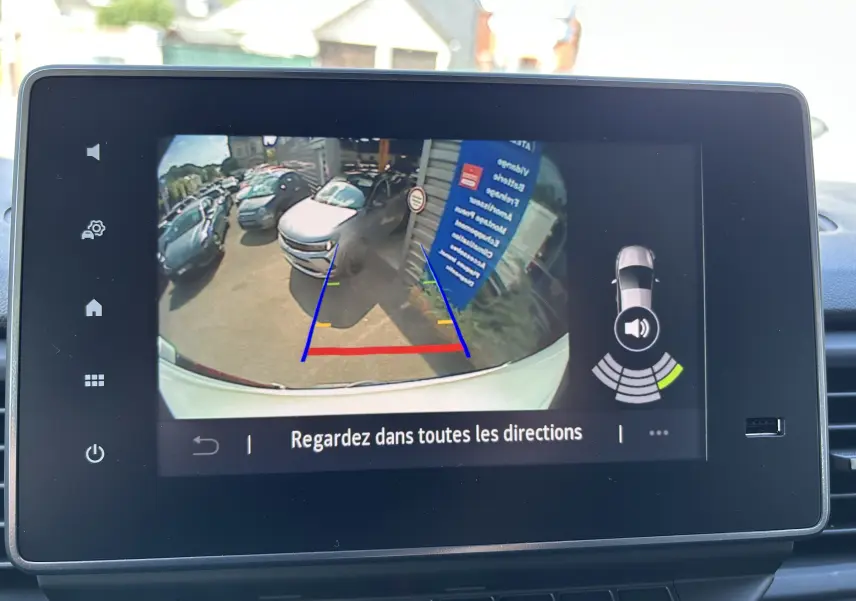 Écran de caméra de recul du Renault Trafic blanc montrant l’arrière avec lignes de guidage colorées et obstacles proches.