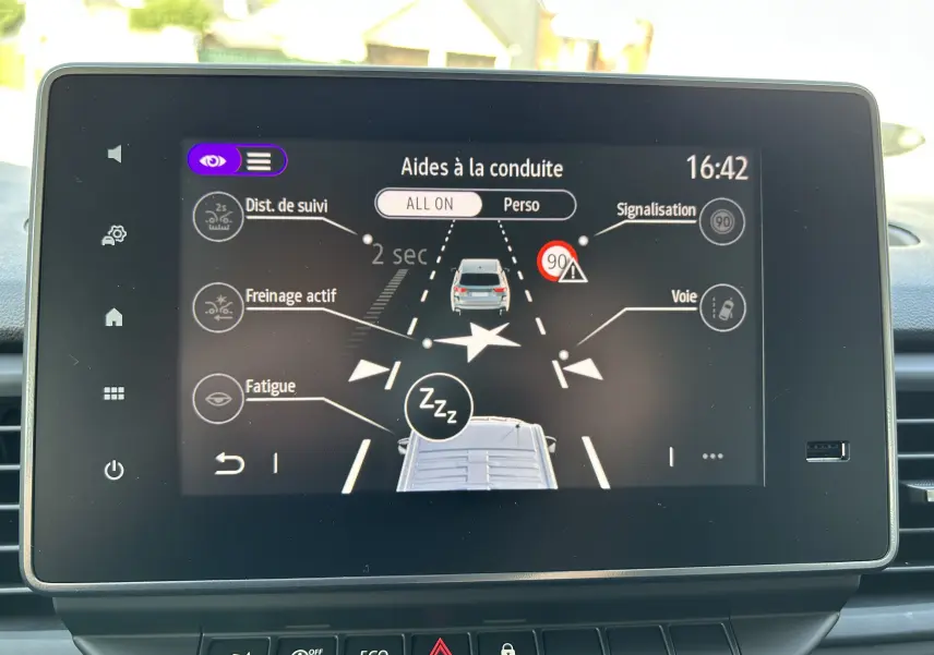Écran tactile intérieur du Renault Trafic blanc montrant les aides à la conduite avec alertes fatigue et freinage actif.