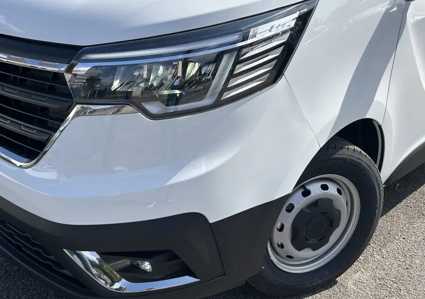 Gros plan sur l’avant droit blanc du Renault Trafic avec phare LED et jante acier simple.