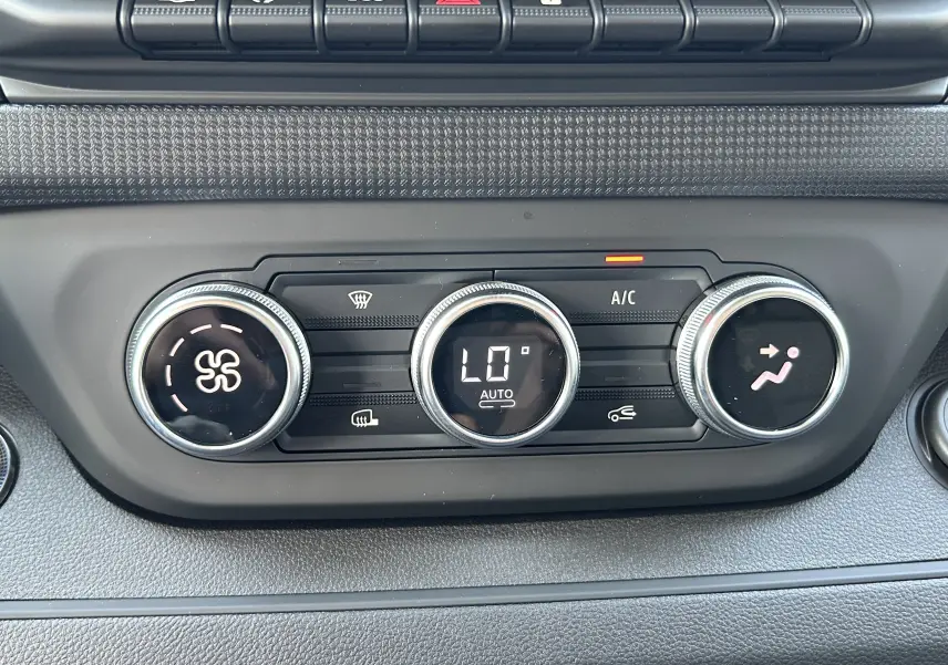 Gros plan sur les commandes de climatisation automatique du tableau de bord du Renault Trafic cabine approfondie blanc.