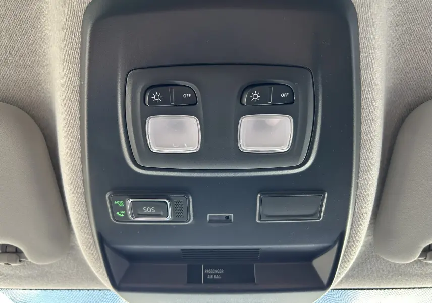 Vue en gros plan du plafonnier intérieur noir avec commandes d’éclairage et bouton SOS du Renault Trafic blanc.