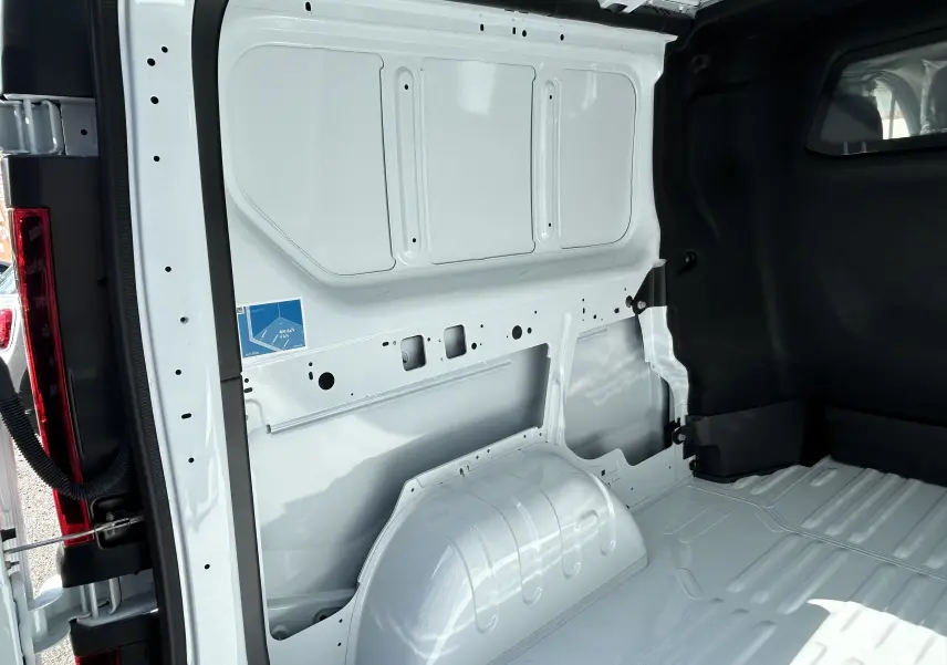 Vue intérieure arrière droite du Renault Trafic cabine approfondie blanc, montrant la paroi métallique et le plancher nu du coffre.