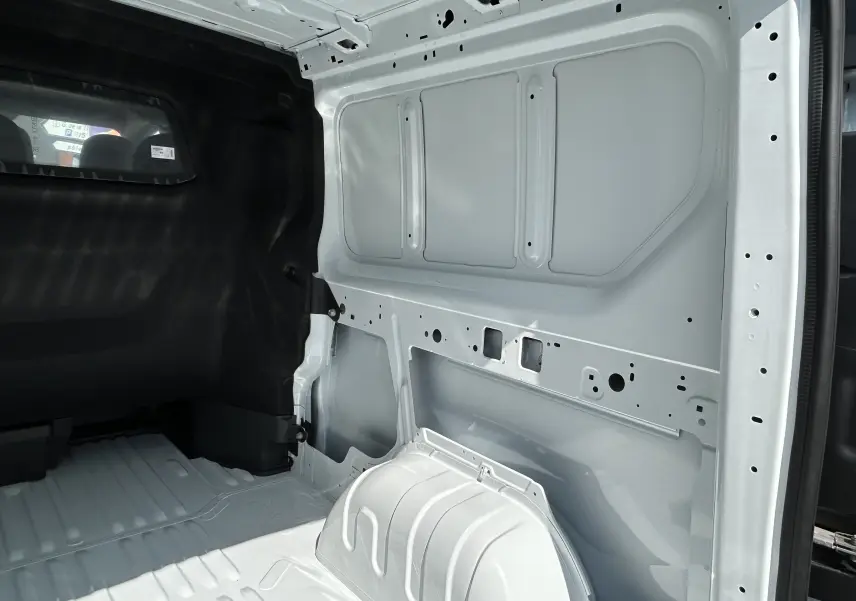 Vue intérieure arrière droite du Renault Trafic cabine approfondie blanc, montrant la paroi métallique nue et le plancher du compartiment.