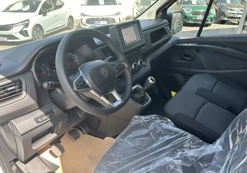 Vue intérieure côté conducteur du Renault Trafic blanc, montrant le volant multifonction, la boîte manuelle et l'écran tactile central.