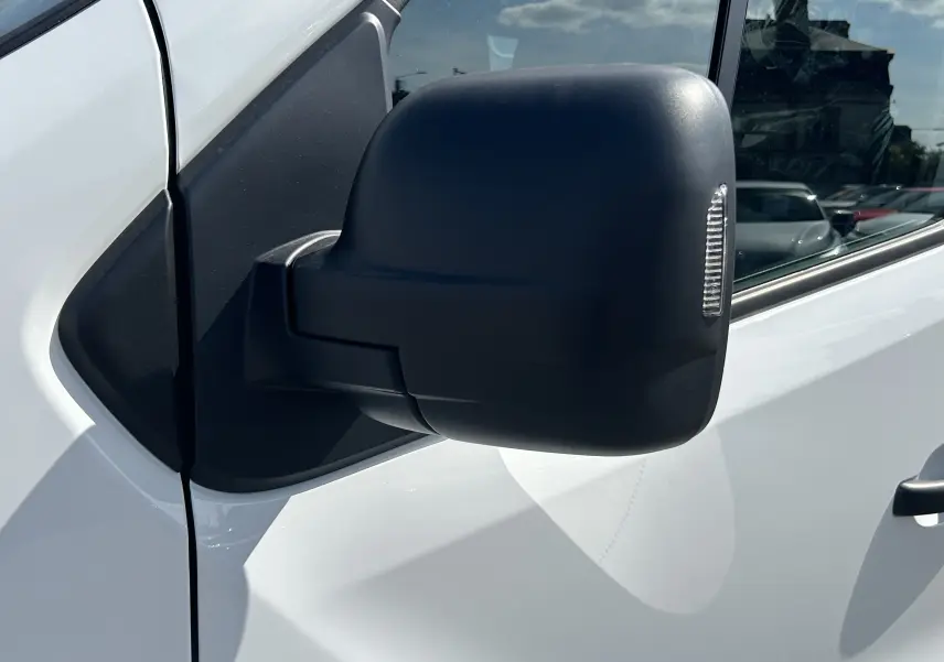 Rétroviseur latéral droit noir sur Renault Trafic cabine approfondie blanc, vue rapprochée côté conducteur.