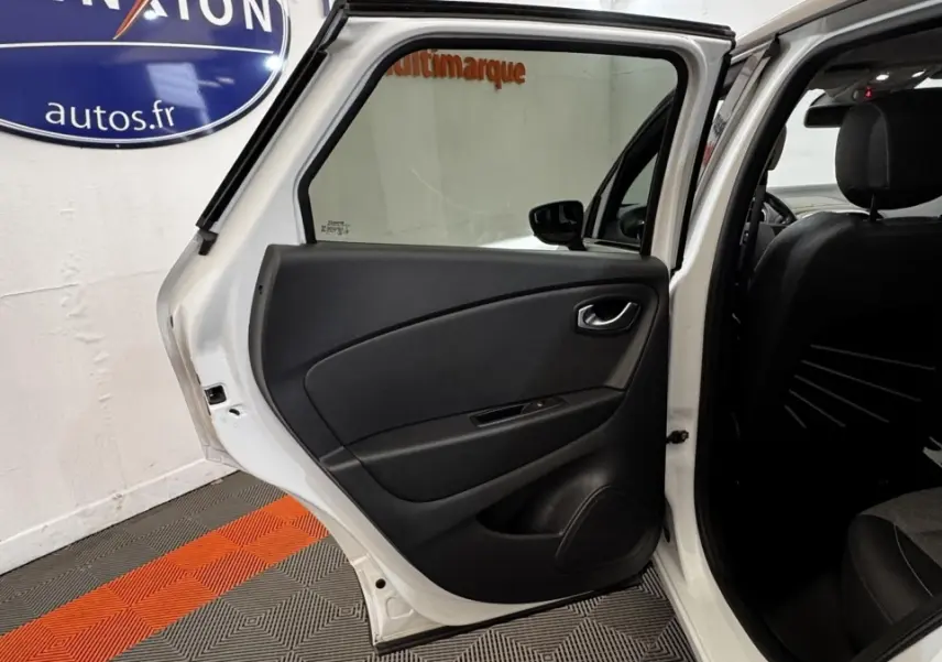 Vue intérieure de la porte arrière gauche ouverte d’un Renault Captur blanc, montrant la garniture noire et l’habitacle sombre.
