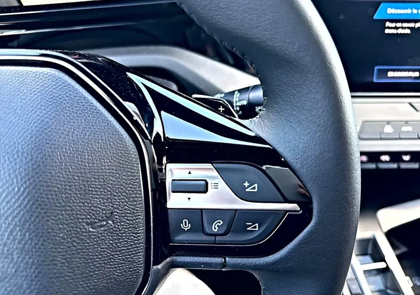 Gros plan sur le volant multifonction noir de la Peugeot 308 2025 avec commandes audio et téléphone intégrées.
